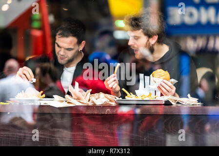 Londres, Royaume-Uni - 12 septembre 2018 : deux hommes guy friends sitting in cafe restauration rapide à l'extérieur contre la fenêtre, reflet de Brewer street à Brixton Banque D'Images