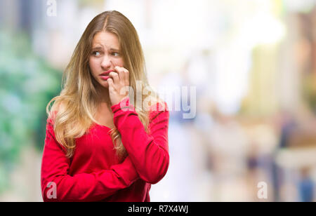 Belle jeune femme blonde wearing red sweater sur fond isolé à souligné et nerveux avec les mains sur la bouche de mordre les ongles. Problèmes d'anxiété Banque D'Images