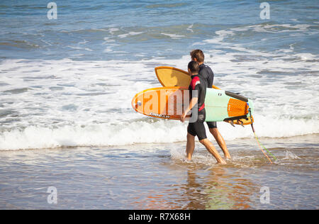 Surfers walking on beach transportant des planches. Banque D'Images