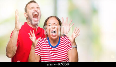 L'âge moyen hispanic couple dans l'amour sur fond isolé et fou fou célèbre pour le succès avec les bras levés et les yeux clos des cris excités. Banque D'Images