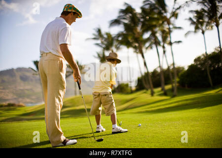 Golfeur mâle regarde son jeune fils jouer au golf. Banque D'Images