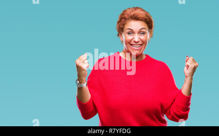 Atrractive redhead caucasian woman wearing winter sweater sur fond isolé célébrant surpris et étonné de la réussite avec les bras lever Banque D'Images