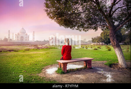 Femme en rouge assis sur le banc à Mehtab Bagh et à la recherche au Taj Mahal à Agra, Uttar Pradesh, Inde Banque D'Images