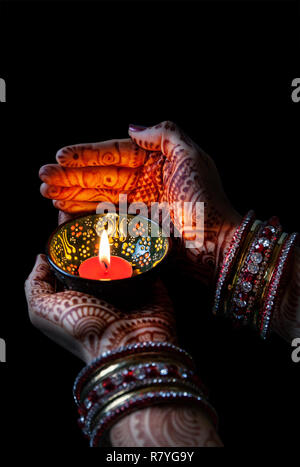 La main de femme tenant au henné bougie allumée isolé sur fond noir avec le chemin de détourage Banque D'Images