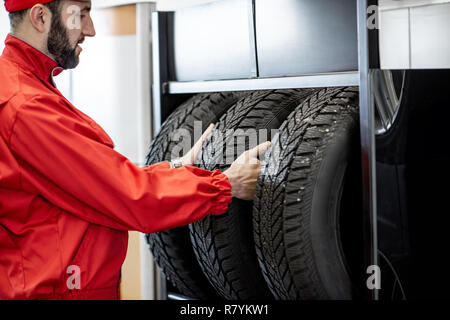 En voiture prendre l'uniforme rouge nouvelle roue de l'étagère du magasin de roue Banque D'Images