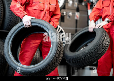 Les travailleurs dans l'exécution uniforme des pneus neufs à la location de service ou magasin, close-up view Banque D'Images