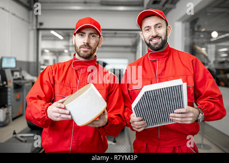 Mécanicien Auto en uniforme rouge et pour tenir debout au filtre à air de voiture Banque D'Images