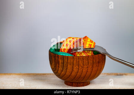 Ruban à mesurer dans un bol en bois et de la fourchette. Concept de l'alimentation et la perte de poids. Banque D'Images