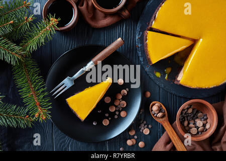 Tranches de mangue chocolat Gâteau au fromage. un morceau d'un gâteau servi sur une plaque noire avec fourchette et dessert chocolat. sapin et tasses avec du café sur un Banque D'Images