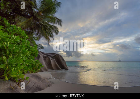 Coucher du soleil sur la plage pittoresque de rêve à anse georgette sur Praslin sur les seychelles. Un gros rocher de granit, l'eau turquoise, des palmiers et un ciel romantique.. Banque D'Images