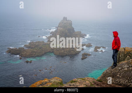 Veste imperméable en touriste solitaire debout sur le haut d'une falaise et admirer les formations rocheuses sur la fin des terres - la plus occidentale de Fra Banque D'Images