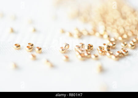 Golden seed beads éparpillés sur fond textile close up Banque D'Images