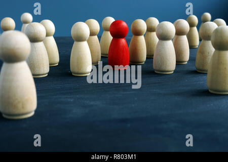 Figures en bois et un rouge figure. Être différent. Se démarquer de la foule. Banque D'Images