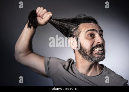 Concept de la colère, l'homme tenir ses cheveux longs dans sa main studio shot Banque D'Images