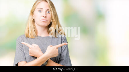 Belle jeune femme portant des T-shirt oversize sur fond isolé en pointant sur les deux côtés avec les doigts, direction différente d'accord Banque D'Images