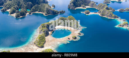 Les récifs coralliens peu profonds à distance surround îles calcaires à Raja Ampat, en Indonésie. Cette région riche en biodiversité, est connu comme le "cœur du Triangle de Corail.' Banque D'Images