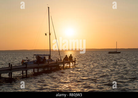 Jetty et historique (bateaux à voile Auswanderer) sur le lac Steinhude au coucher du soleil. Basse-saxe, Allemagne Banque D'Images