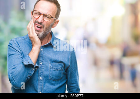 L'âge moyen le senior man wearing glasses sur fond isolé de toucher la bouche avec la main avec expression douloureuse à cause de maux ou dentaire j Banque D'Images