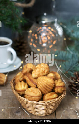 Sablés faits maison dans diverses formes, rempli de caramel sur l'arrière-plan de branches de sapin et de guirlandes. Banque D'Images