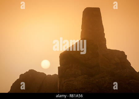 Misty scène sur Stiperstones, Shropshire, en une seule couleur, avec le soleil visible, et le trig point. Banque D'Images