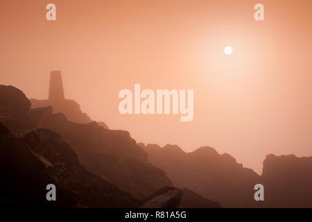 Misty scène sur Stiperstones, Shropshire, en une seule couleur, avec le soleil visible, et le trig point. Banque D'Images