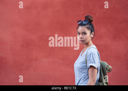 Young Asian woman debout devant un mur à l'extérieur Banque D'Images