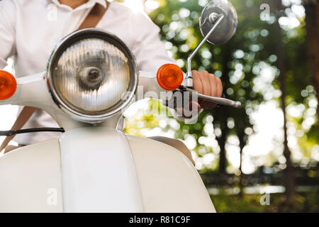 Portrait d'un jeune homme assis sur une moto à l'extérieur Banque D'Images