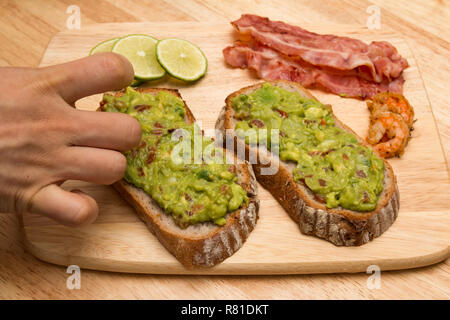 Le guacamole avec du pain et de l'avocat sur la planche à découper en bois Banque D'Images