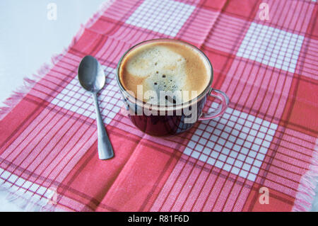 Espresso verre sur une serviette à carreaux rouges, le café du matin. Banque D'Images