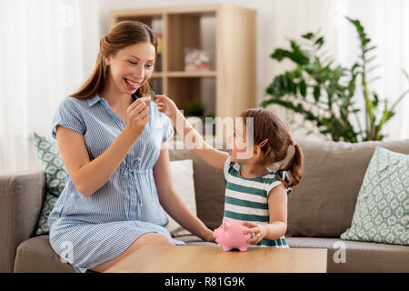 Mère et fille enceinte avec piggy bank Banque D'Images