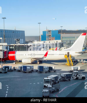 Avion chargement parqué par bâtiment de l'aéroport de Copenhague, les escaliers et les porte-bagages à proximité Banque D'Images