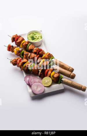 Poulet tikka /incliner kebab. Plat indien traditionnel cuit sur charbon de bois et des flammes, assaisonnée et agrémentée de couleurs vives. servi avec salade verte et chutney Banque D'Images