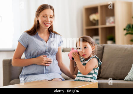 Mère et fille enceinte avec piggy bank Banque D'Images