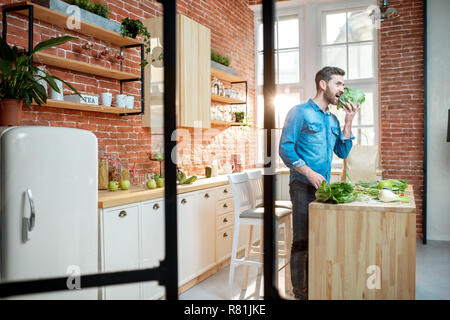 La cuisson des aliments sains l'homme debout sur la cuisine de la magnifique appartement loft Banque D'Images