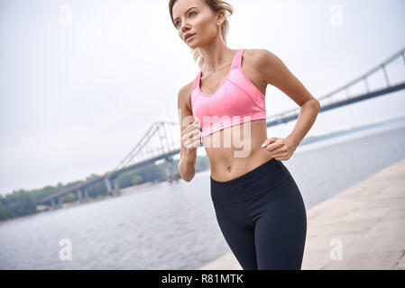 Sérieux au sujet de rester en forme. Vue de dessus de jeune femme en vêtements de sport jogging lors de l'exercice en plein air Banque D'Images