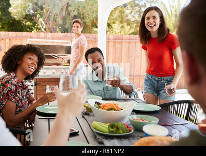 Les amis des jeunes adultes assis à l'extérieur pour barbecue le midi Banque D'Images