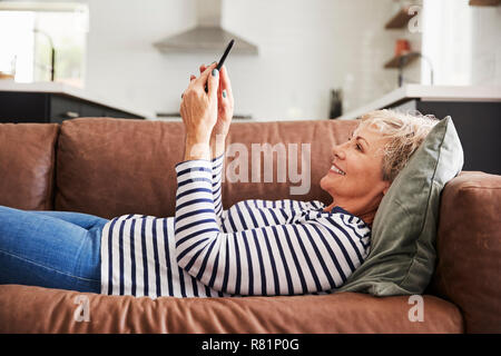 Hauts femme blanche allongée sur table à l'aide d'accueil téléphone intelligent Banque D'Images