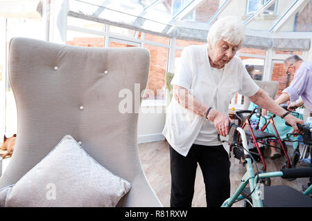 Senior Woman Using aide à la mobilité dans le salon de la maison de retraite Banque D'Images