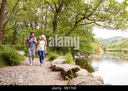 Couple de la randonnée le long de la rivière par le chemin au Royaume-Uni Lake District Banque D'Images