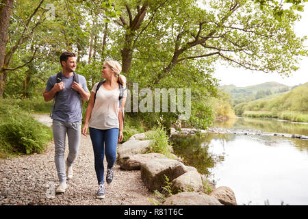 Couple de la randonnée le long de la rivière par le chemin au Royaume-Uni Lake District Banque D'Images