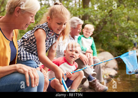 Les grands-parents avec petits-enfants avec des filets de pêche en rivière en UK Lake District Banque D'Images