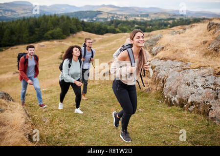 Groupe ethnique Multi de cinq jeunes amis adultes randonnées à travers un champ en montant vers le sommet, Close up Banque D'Images