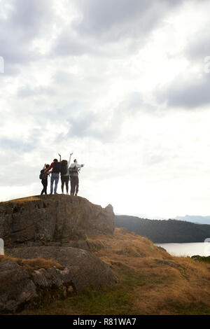 La silhouette d'un groupe de jeunes amis adultes célébrer son arrivée au sommet après une randonnée en montagne Banque D'Images