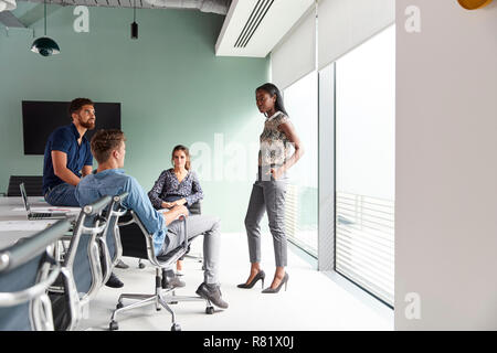 Habillé décontracté hommes et de femmes d'affaires ayant Réunion informelle dans la salle moderne Banque D'Images