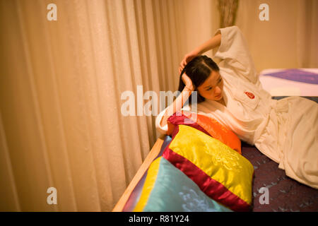 Femme allongée sur un canapé dans un peignoir. Banque D'Images