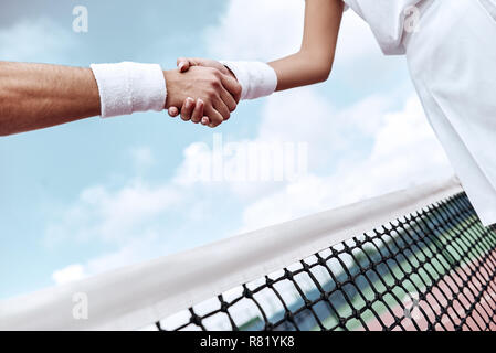 Se serrer la main après un bon jeu. Close-up de l'homme et de la femme en serrant la main bracelet sur le filet de tennis Banque D'Images