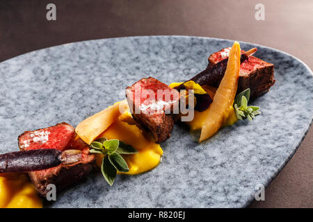 Filet de chevreuil avec purée de patate douce, carotte pourpre blanchies, confiture de coing avec du vin Banque D'Images