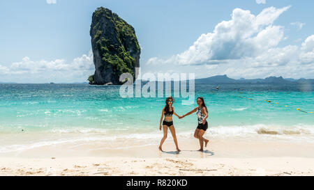 Mère et fille dansant sur une plage tropicale avec island dans l'arrière-plan Banque D'Images