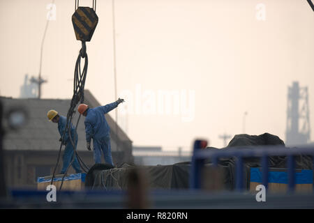 Deux male construction workers raccordement de câbles à une grue dans un chantier maritime. Banque D'Images