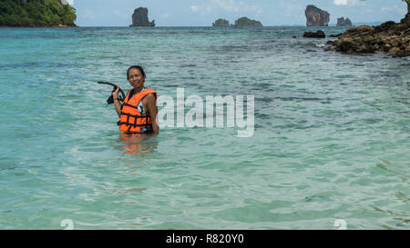 Femme debout dans l'eau en gilet orange masque et un tuba holding Banque D'Images